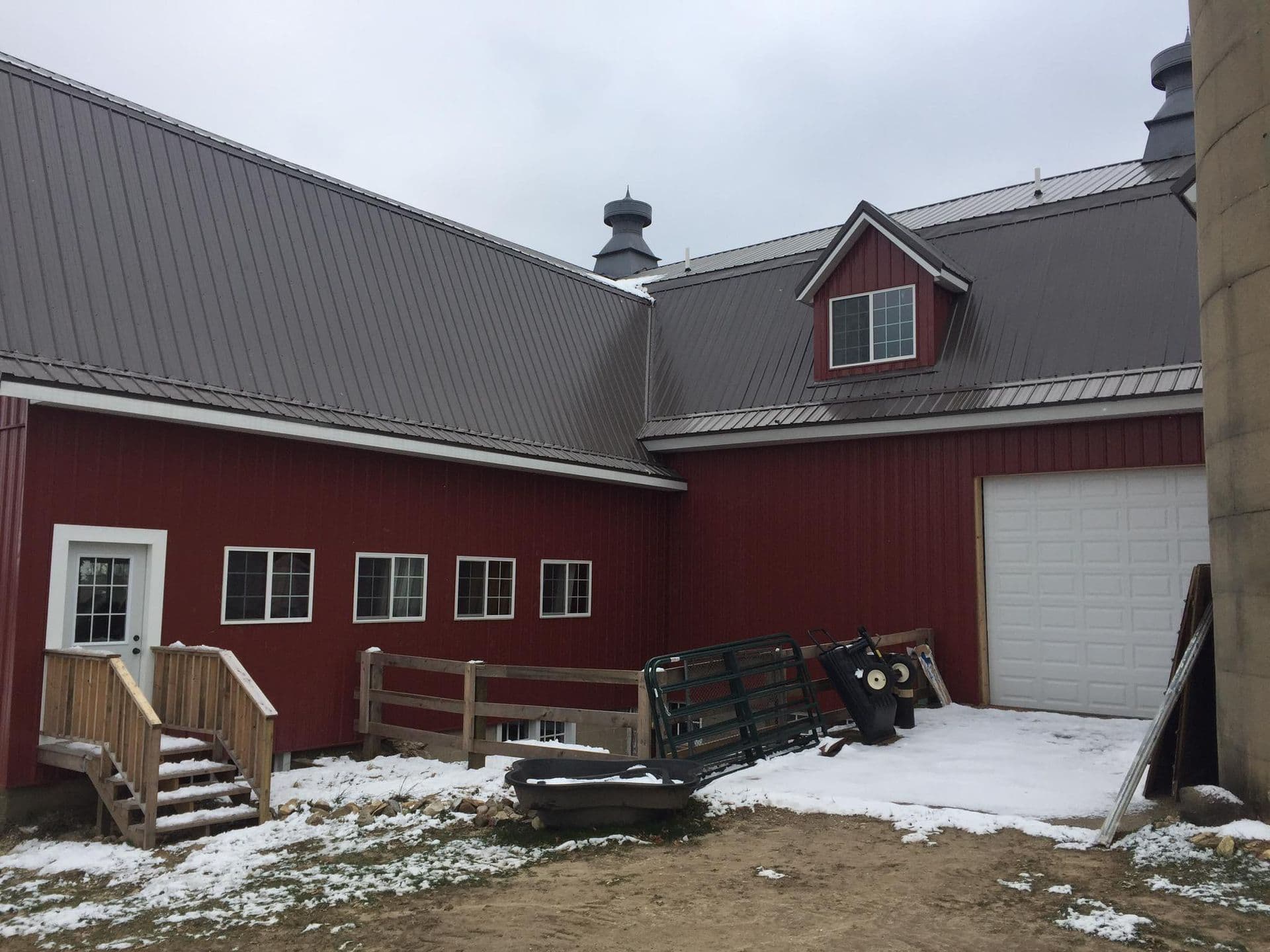 A red barn with new siding and gray metal roofing.