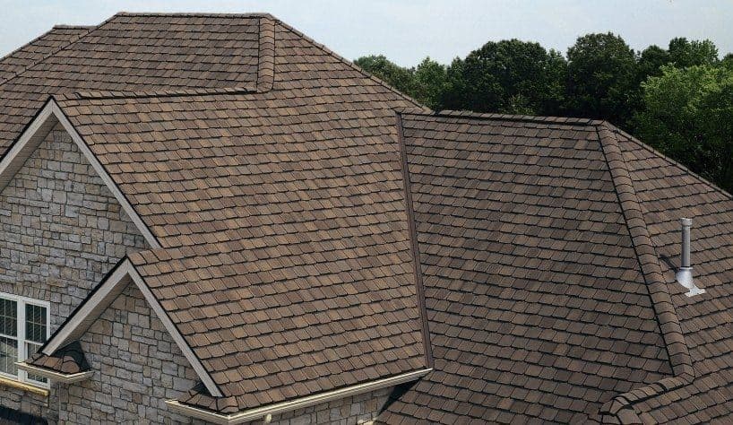 A stone house with asphalt shingle roofing.